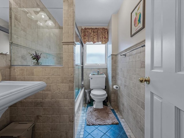 18 Ashland Ave, New Hyde Park, NY 11040 - bathroom with tile walls, toilet, tile patterned flooring, bath / shower combo with glass door, and a wainscoted wall