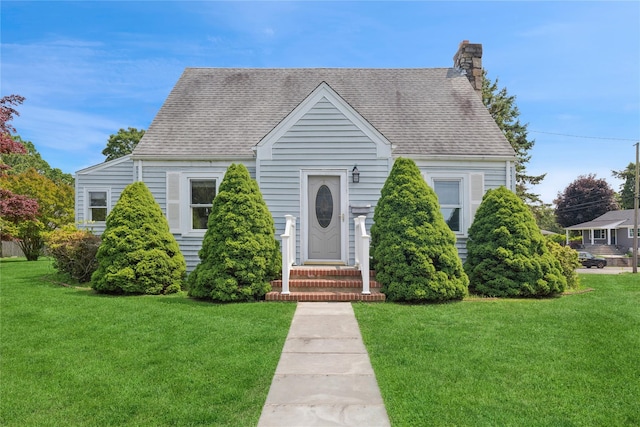 1295 Washington Ave, Greenport, NY 11944 - view of front of house featuring a front lawn, a chimney, and roof with shingles