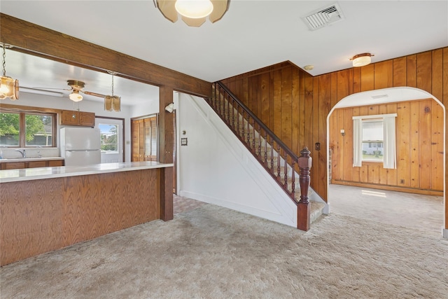 1295 Washington Ave, Greenport, NY 11944 - kitchen featuring freestanding refrigerator, ceiling fan, light colored carpet, a sink, and wooden walls