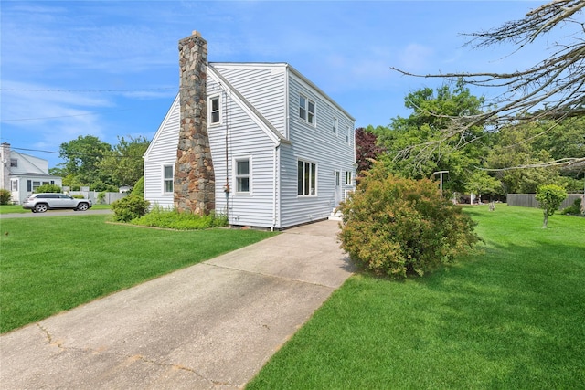 1295 Washington Ave, Greenport, NY 11944 - view of home's exterior featuring a chimney, a lawn, and concrete driveway