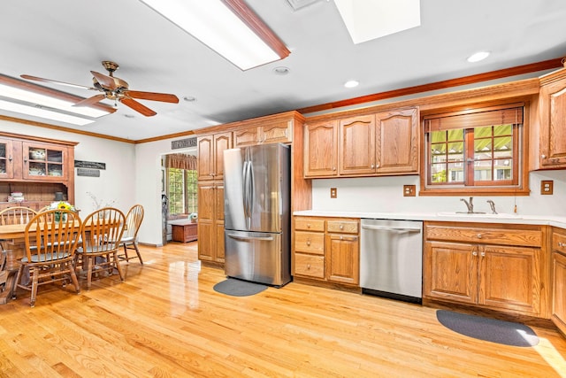 2A Suffern Ln, Garnerville, NY 10923 - kitchen featuring appliances with stainless steel finishes, a skylight, crown molding, a sink, and light wood-style flooring