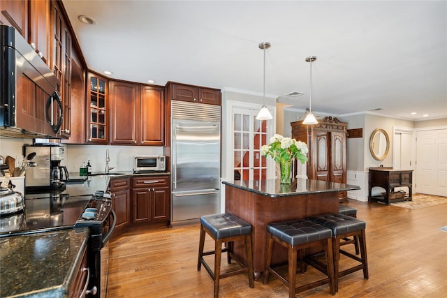 4 Valley Rd, Syosset, NY 11791 - kitchen featuring stainless steel appliances, a breakfast bar, light wood-style floors, ornamental molding, and a center island