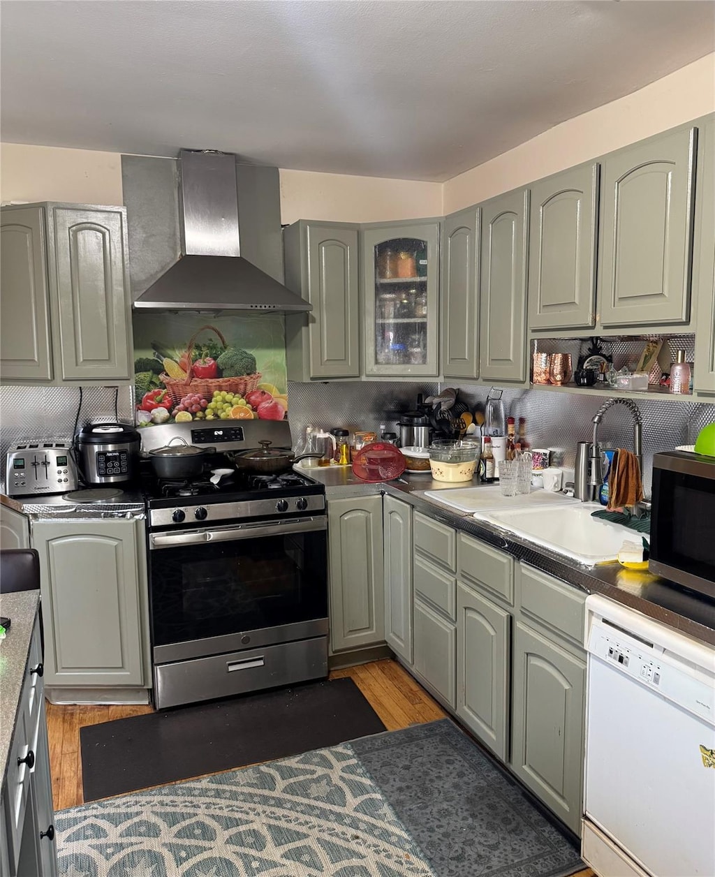1 Winthrop St, Islip, NY 11751 - kitchen featuring appliances with stainless steel finishes, wall chimney exhaust hood, light wood-type flooring, and a sink