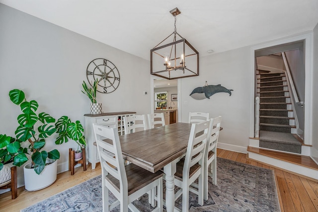 85 Fairmount St, Huntington, NY 11743 - dining area featuring light wood-style flooring, stairway, a chandelier, and baseboards