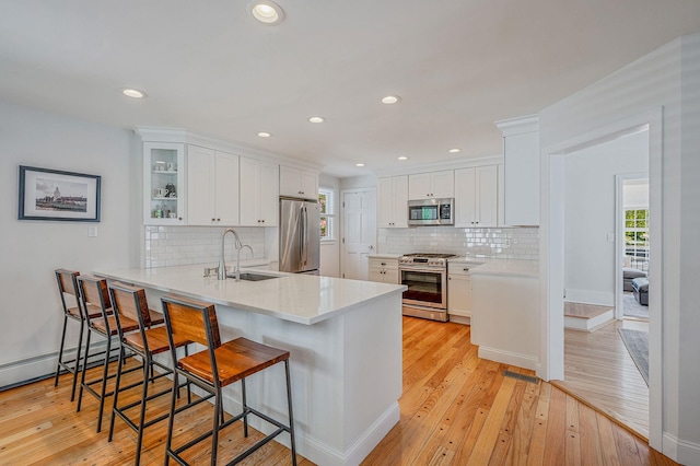 85 Fairmount St, Huntington, NY 11743 - kitchen with appliances with stainless steel finishes, a sink, white cabinetry, light wood-style flooring, and a kitchen breakfast bar