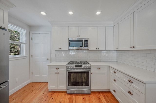 85 Fairmount St, Huntington, NY 11743 - kitchen with appliances with stainless steel finishes, white cabinets, baseboards, light wood finished floors, and backsplash