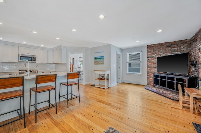 85 Fairmount St, Huntington, NY 11743 - kitchen with stainless steel microwave, a kitchen breakfast bar, light countertops, baseboards, and light wood finished floors