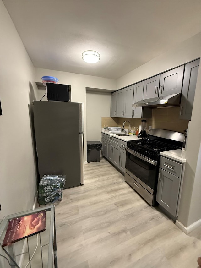 57-54 Xenia St, Corona, NY 11368 - kitchen with appliances with stainless steel finishes, under cabinet range hood, gray cabinets, light countertops, and light wood-style flooring
