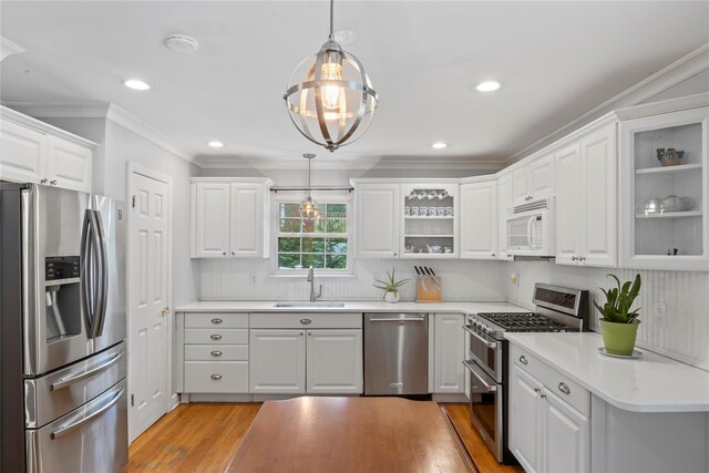 319 Thompson St, Port Jefferson, NY 11777 - kitchen with appliances with stainless steel finishes, a sink, ornamental molding, white cabinets, and hanging light fixtures
