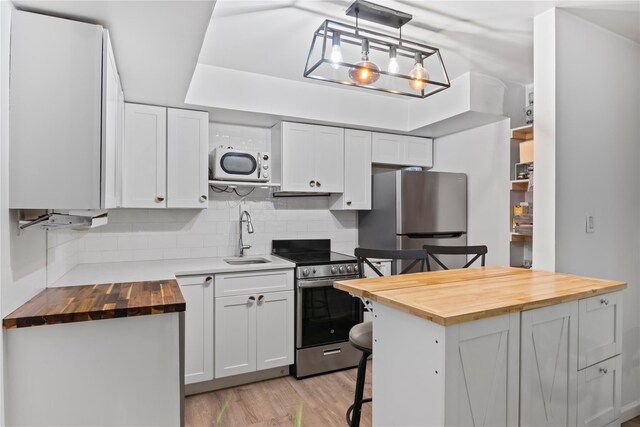 319 Thompson St, Port Jefferson, NY 11777 - kitchen featuring wood counters, appliances with stainless steel finishes, a sink, white cabinets, and tasteful backsplash