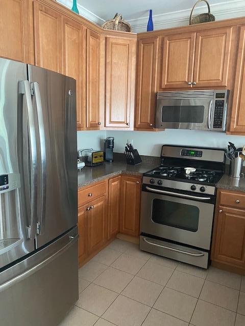 28 Torrey Pine Ln, Bay Shore, NY 11706 - kitchen featuring stainless steel appliances, light tile patterned flooring, dark countertops, and brown cabinets
