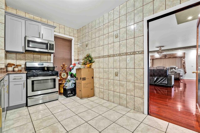 114-11 86th Ave, Richmond Hill North, NY 11418 - kitchen featuring stainless steel appliances, light tile patterned floors, gray cabinets, and tile walls