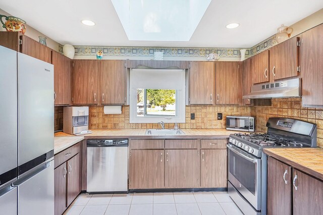1340 Stony Brook Rd, Stony Brook, NY 11790 - kitchen featuring appliances with stainless steel finishes, under cabinet range hood, backsplash, a skylight, and recessed lighting