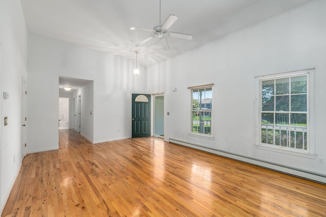 67 Fairway Dr, Wading River, NY 11792 - empty room featuring a baseboard radiator, a towering ceiling, healthy amount of natural light, a ceiling fan, and wood finished floors