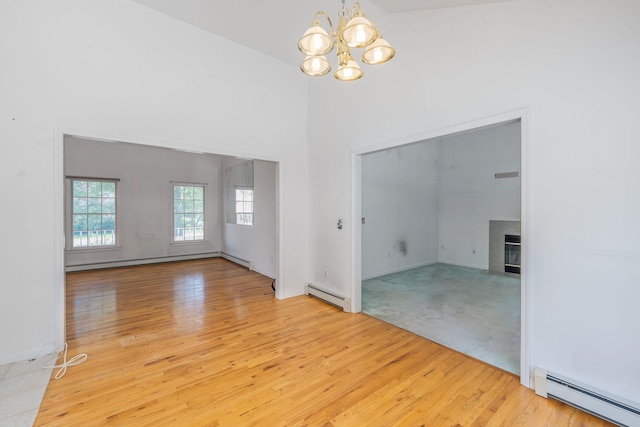 67 Fairway Dr, Wading River, NY 11792 - spare room featuring a baseboard heating unit, a chandelier, healthy amount of natural light, and a towering ceiling
