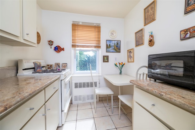 490 Atlantic Ave Unit 103, East Rockaway, NY 11518 - kitchen with white range with gas cooktop, radiator, white cabinets, light tile patterned floors, and black microwave