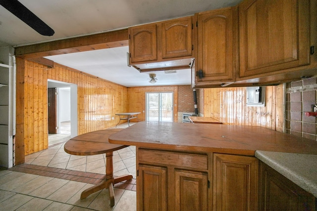 3 Avenue E, Godeffroy, NY 12729 - kitchen featuring brown cabinetry, light tile patterned floors, wooden walls, a peninsula, and a wood stove