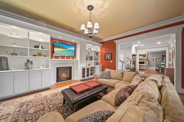 383 Illington Rd, Ossining, NY 10562 - living area with a warm lit fireplace, ornamental molding, a chandelier, wood finished floors, and built in shelves