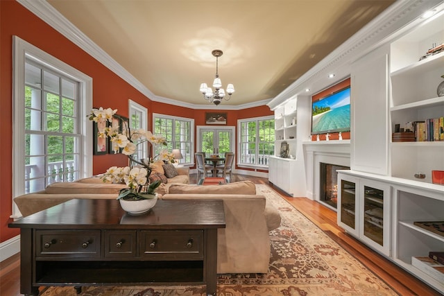 383 Illington Rd, Ossining, NY 10562 - living room featuring a chandelier, crown molding, wood finished floors, built in shelves, and a warm lit fireplace