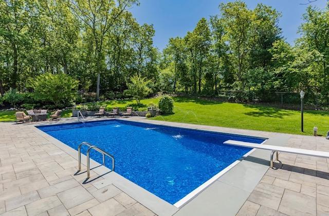 10 Woods Edge Ct, Hauppauge, NY 11788 - outdoor pool featuring a lawn, a patio area, a diving board, and view of wooded area