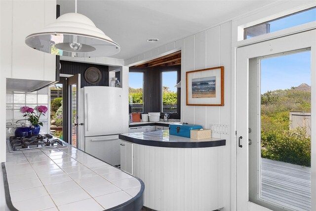 0 Atlantic Walk, Water Island, NY 11772 - kitchen featuring freestanding refrigerator, stainless steel gas stovetop, tile countertops, white cabinetry, and a peninsula
