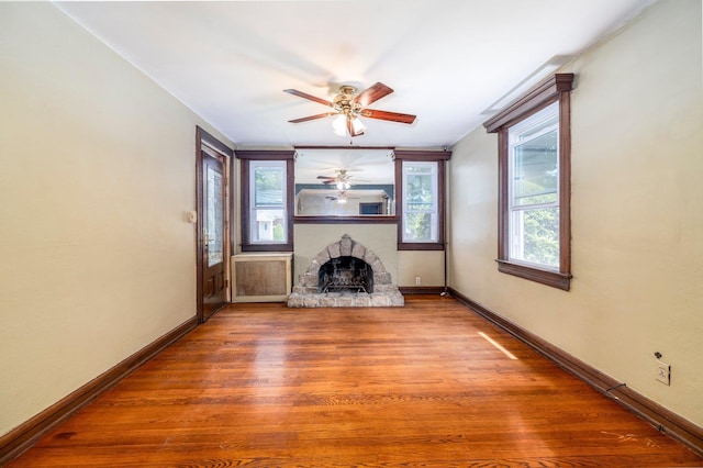 2430 Loft Ave, Baldwin, NY 11510 - unfurnished living room featuring ceiling fan, a fireplace with raised hearth, and wood finished floors