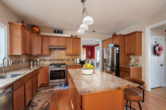 2 Undset Ct, Dix Hills, NY 11746 - kitchen with stainless steel appliances, under cabinet range hood, light wood finished floors, a kitchen island, and light stone countertops