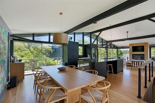 490 Tarpon Walk, Fire Island Pines, NY 11782 - dining room with floor to ceiling windows, light wood-style floors, a fireplace, plenty of natural light, and a ceiling fan