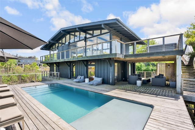490 Tarpon Walk, Fire Island Pines, NY 11782 - rear view of house with board and batten siding, a balcony, an outdoor pool, and a wooden deck