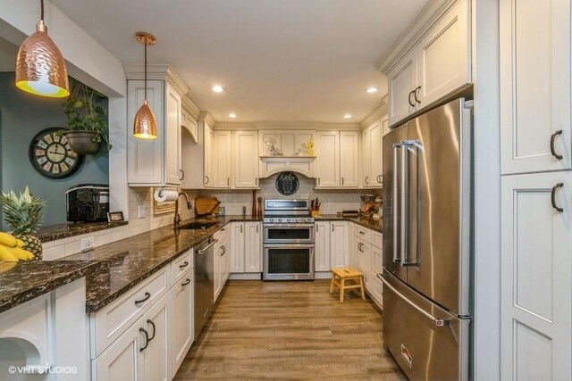 2976 Ruth Rd, Wantagh, NY 11793 - kitchen featuring stainless steel appliances, a sink, wood finished floors, tasteful backsplash, and decorative light fixtures