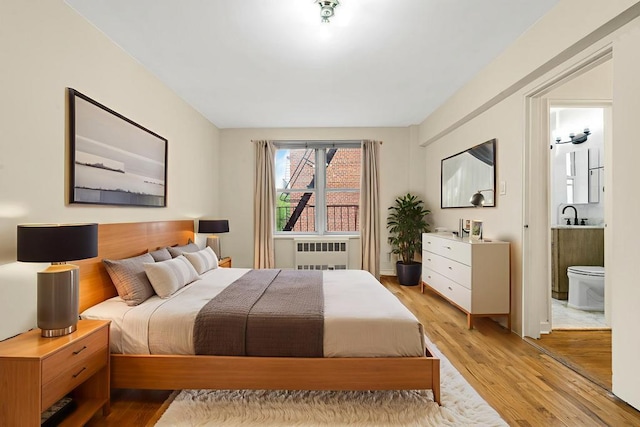 72-10 112th St Unit 5B, Forest Hills, NY 11375 - bedroom with radiator, light wood finished floors, and ensuite bath
