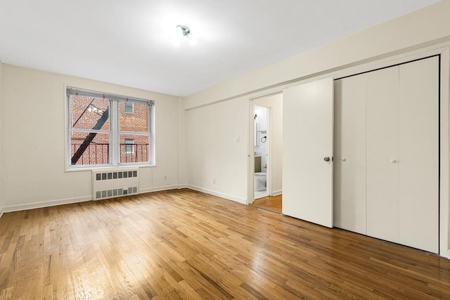 72-10 112th St Unit 5B, Forest Hills, NY 11375 - unfurnished bedroom featuring radiator heating unit, wood-type flooring, baseboards, and a closet