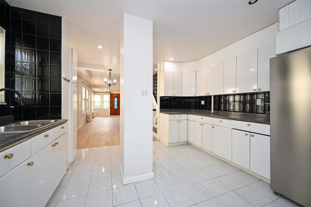 43-24 219th St, Bayside, NY 11361 - kitchen featuring freestanding refrigerator, dark countertops, a sink, light tile patterned flooring, and tasteful backsplash