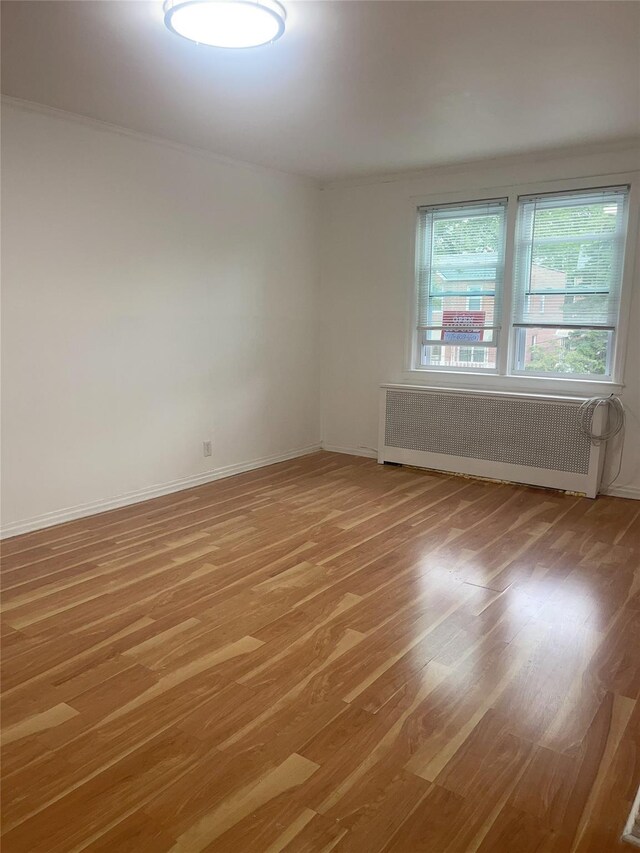 6848 Selfridge St, Forest Hills, NY 11375 - empty room with radiator, light wood finished floors, and baseboards