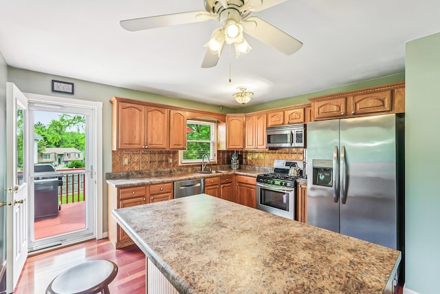 304 Cloverdale Ct, New Windsor, NY 12553 - kitchen with stainless steel appliances, backsplash, a center island, brown cabinets, and a ceiling fan