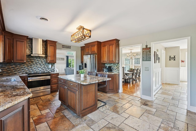 30 Sunrise Rdg, Florida, NY 10921 - kitchen with wall chimney exhaust hood, appliances with stainless steel finishes, a chandelier, stone tile floors, and tasteful backsplash
