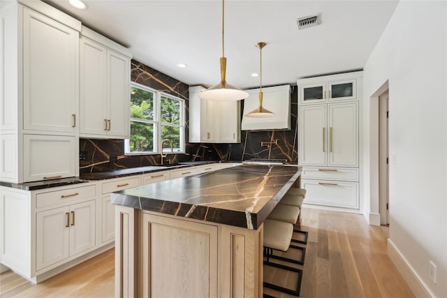 3 Sugar Maple Ct, Dix Hills, NY 11746 - kitchen with dark countertops, light wood-style flooring, decorative backsplash, a center island, and a breakfast bar area