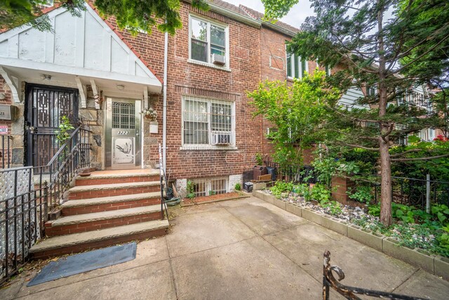 32-23 76th St, East Elmhurst, NY 11370 - view of property featuring brick siding and a patio