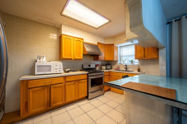 32-23 76th St, East Elmhurst, NY 11370 - kitchen featuring stainless steel gas stove, range hood, white microwave, a sink, and light countertops