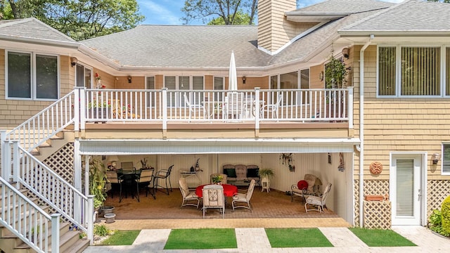 6 Ring Neck Ct, Wading River, NY 11792 - back of house featuring stairway, a shingled roof, a patio, a chimney, and outdoor dining space