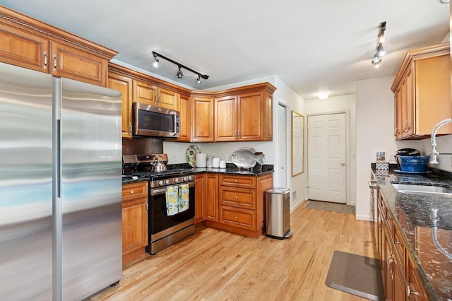 26405 Main Rd, Cutchogue, NY 11935 - kitchen with stainless steel appliances, track lighting, brown cabinets, light wood-style flooring, and dark stone countertops