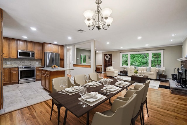 26 Crown Hill Rd, Wappingers Falls, NY 12590 - dining area with light wood-style flooring, a chandelier, a brick fireplace, recessed lighting, and crown molding