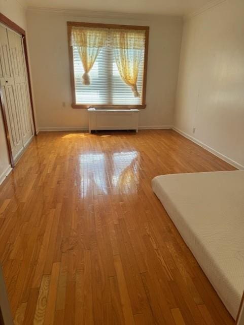 3591 161st St Unit 2J, Flushing, NY 11358 - unfurnished bedroom featuring crown molding, light wood finished floors, baseboards, and a closet