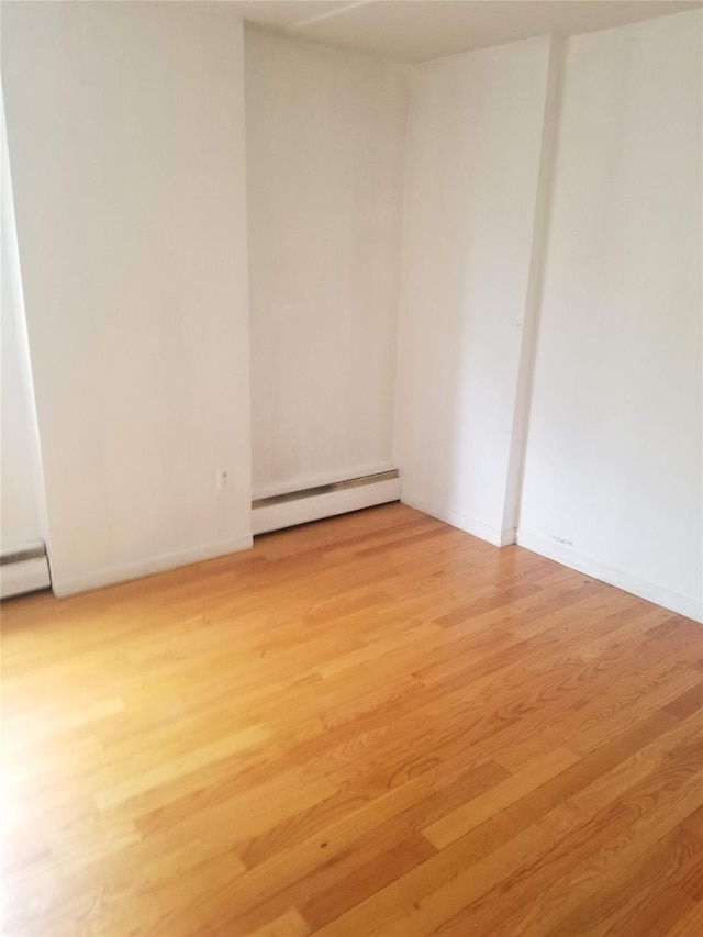 134-46 Maple Ave Unit 1C, Flushing, NY 11355 - empty room with a baseboard heating unit and light wood-style floors