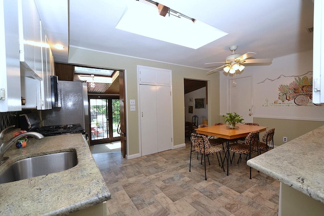 1318 Brooklyn Blvd, Bay Shore, NY 11706 - kitchen featuring a skylight, a ceiling fan, stainless steel range with gas cooktop, stone finish floors, and white cabinets