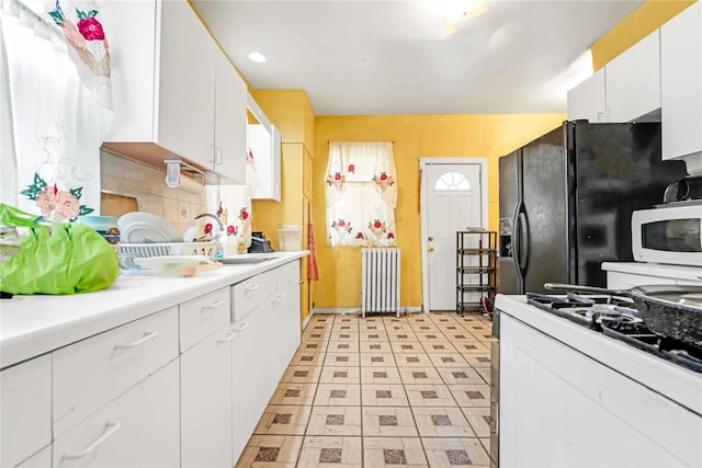 11480 178th Pl, Addisleigh Park, NY 11434 - kitchen with radiator, a sink, gas stove, white microwave, and white cabinetry