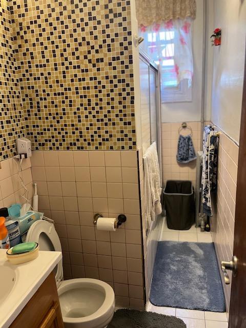 5436 Nurge Ave, Maspeth, NY 11378 - bathroom with tile walls, tile patterned floors, toilet, and vanity