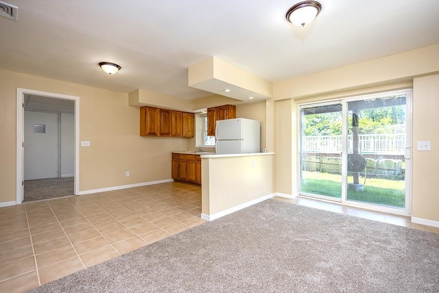 2 Joseph St, West Haverstraw, NY 10993 - kitchen featuring freestanding refrigerator, brown cabinets, light tile patterned floors, baseboards, and light countertops