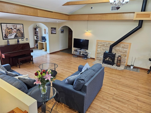 526 Hazel Dr, Woodmere, NY 11598 - living room with arched walkways, a wood stove, lofted ceiling, wood finished floors, and baseboards