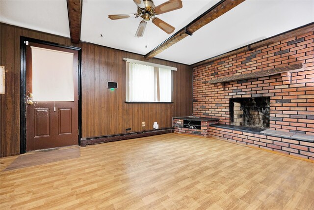 53 Wiltshire Dr, Commack, NY 11725 - unfurnished living room featuring beam ceiling, wood finished floors, wooden walls, a brick fireplace, and a ceiling fan